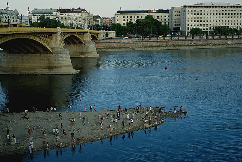 People walk on a sandbar underneath the Danube's Margareth Bridge in downtown Budapest, 5 August, 2026