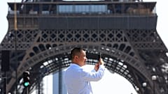 Uma pessoa usa o telemóvel junto à Torre Eiffel, em Paris, na quarta-feira, 31 de agosto de 2022.