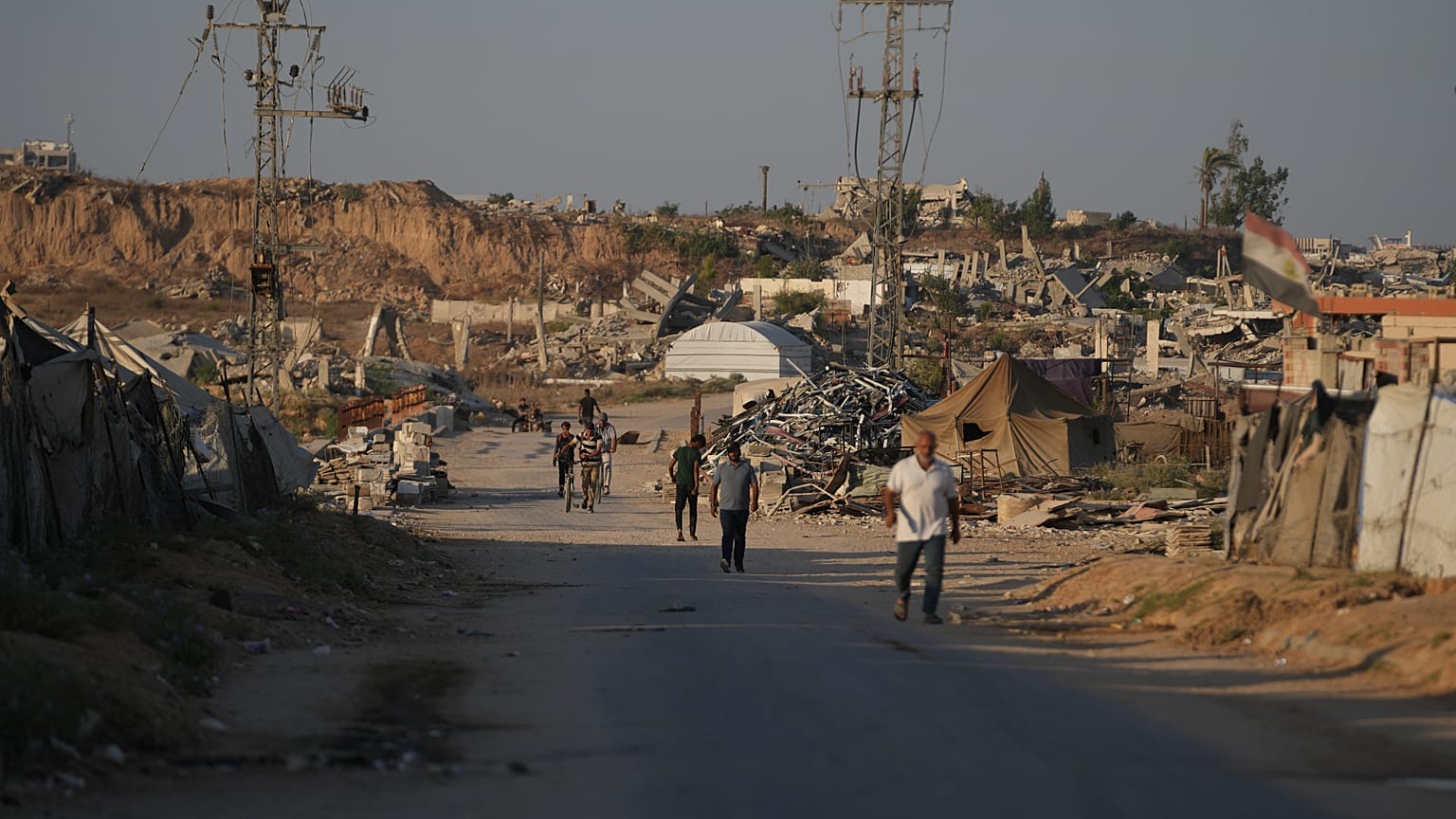 نازحون فلسطينيون يمرون أمام مخيم في النصيرات بوسط قطاع غزة الجمعة 31 يوليو 2026. (AP Photo/عبد الكريم حنا)