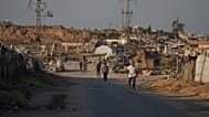 نازحون فلسطينيون يمرون أمام مخيم في النصيرات بوسط قطاع غزة الجمعة 31 يوليو 2026. (AP Photo/عبد الكريم حنا)