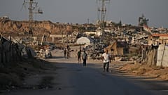 نازحون فلسطينيون يمرون أمام مخيم في النصيرات بوسط قطاع غزة الجمعة 31 يوليو 2026. (AP Photo/عبد الكريم حنا)