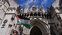 متظاهر يلوح بعلم خارج المحكمة العليا في لندن خلال جلسة استماع كاملة بشأن طلب مراجعة قضائية قدمته منظمة "فلسطين أكشن" ضد حظرها الوشيك، يوم الاثنين 21 يوليو/تموز 2025. (صورة من 