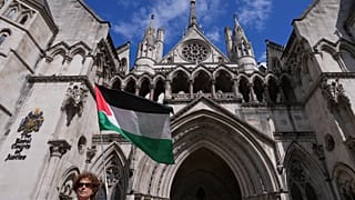 متظاهر يلوح بعلم خارج المحكمة العليا في لندن خلال جلسة استماع كاملة بشأن طلب مراجعة قضائية قدمته منظمة "فلسطين أكشن" ضد حظرها الوشيك، يوم الاثنين 21 يوليو/تموز 2025. (صورة من 