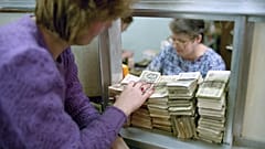A Muscovite woman puts huge amount of useless money (50 and 100 rubles notes) on the bank counter to exchange them in Moscow on Friday, Jan. 25, 1991