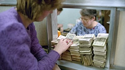A Muscovite woman puts huge amount of useless money (50 and 100 rubles notes) on the bank counter to exchange them in Moscow on Friday, Jan. 25, 1991