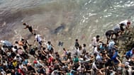 Varias personas caminan por una playa mientras intentan cruzar desde la ciudad marroquí de Fnideq hasta el enclave español de Ceuta, el viernes 31 de julio de 2026.