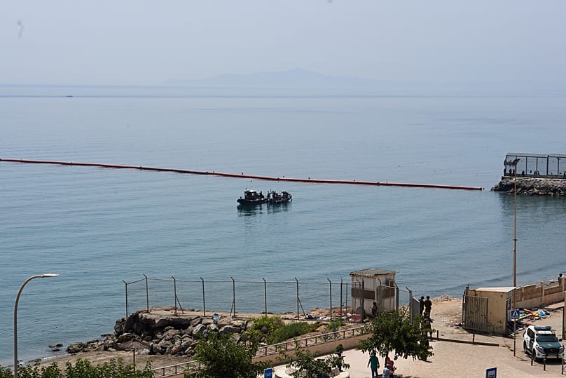 Embarcaciones de la Guardia Civil patrullan junto a barreras flotantes frente a la costa del enclave español de Ceuta, el sábado 1 de agosto de 2026. 