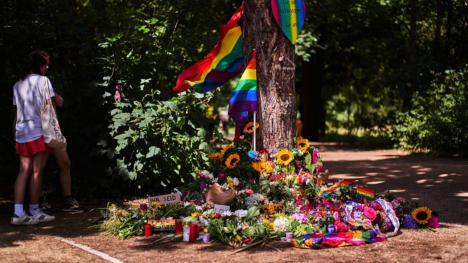 Flores e bandeiras arco-íris colocadas junto a uma árvore no parque Tiergarten, em Berlim, perto do local do atropelamento na Marcha do Orgulho, Alemanha, 27 de julho de 2026