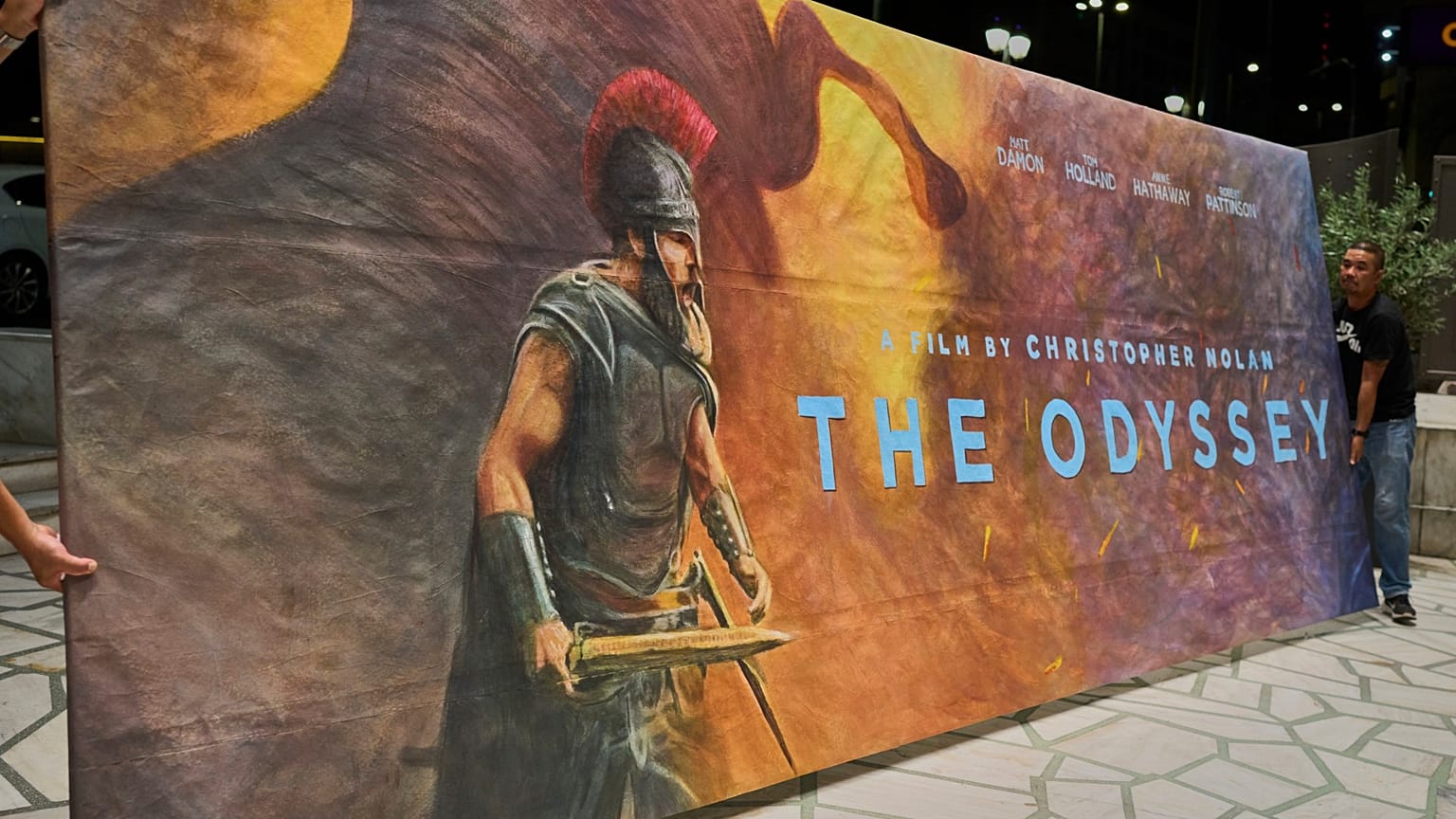Des ouvriers installent une affiche peinte par Virginia Axioti pour le film de Christopher Nolan "The Odyssey", devant le cinéma Athinaion d'Athènes, le 11 juillet 2026.