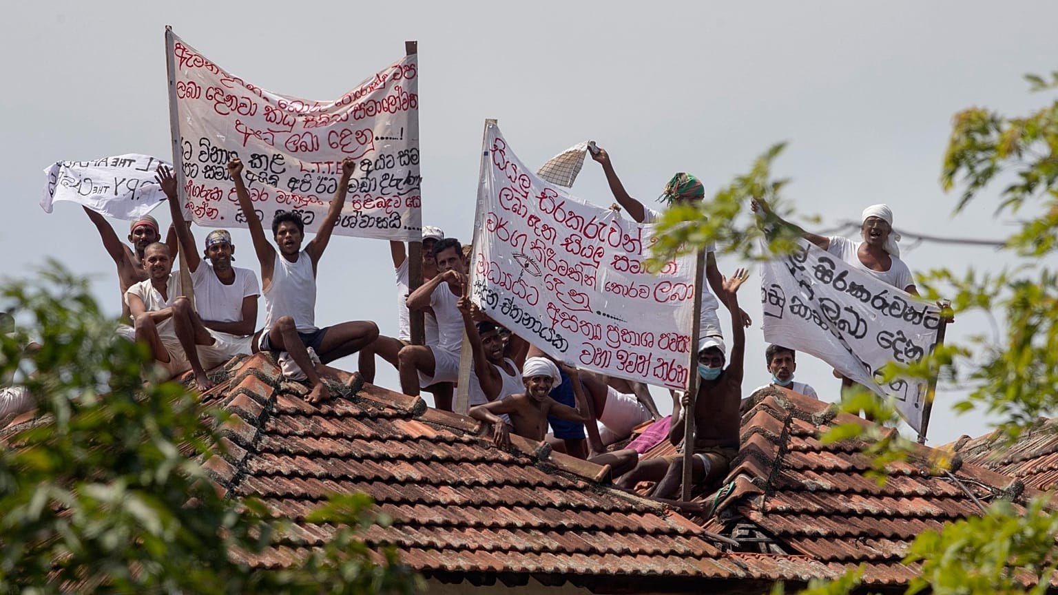 I detenuti nel braccio della morte del carcere di Welikada protestano dal tetto dell’istituto a Colombo esponendo striscioni, 25 giugno 2021.