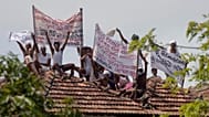 Death-row inmates at Welikada prison protest holding banners from the roof of the prison in Colombo, 25 June, 2021