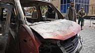 صورة تعبيرية- عناصر أمن سوريون يتفقدون مركبة محترقة بالقرب من فندق "فور سيزونز" عقب وقوع انفجارين هزا المنطقة 