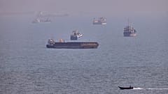 Um pequeno barco passa junto de navios de carga e outras embarcações comerciais fundeadas no estreito de Ormuz, ao largo de Bandar Abbas, no Irão, 5 de agosto de 2026