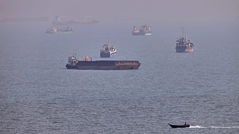A small boat sails past cargo ships and other commercial vessels anchored in the Strait of Hormuz off Bandar Abbas, Iran, Wednesday, Aug. 5, 2026.