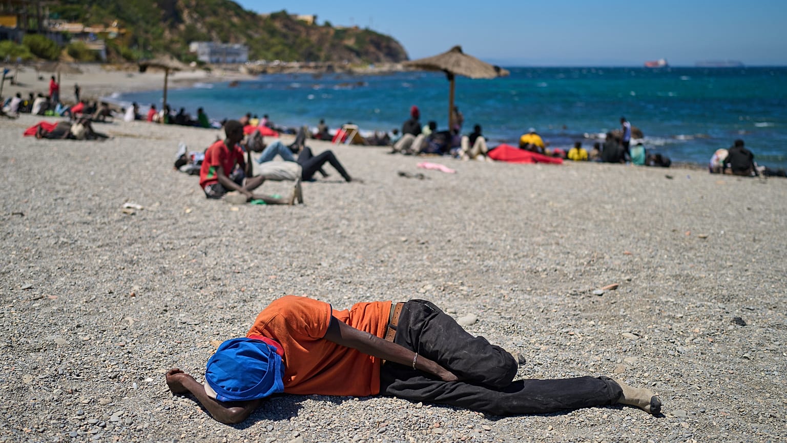 Un migrante que cruzó a España desde Marruecos duerme en una playa del enclave español de Ceuta, el domingo 2 de agosto de 2026. (Foto AP/Bernat Armangue)