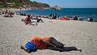 Un migrante que cruzó a España desde Marruecos duerme en una playa del enclave español de Ceuta, el domingo 2 de agosto de 2026. (Foto AP/Bernat Armangue)