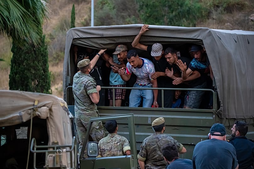 Soldados españoles escoltan hacia la frontera hispano-marroquí a migrantes que habían cruzado a España, para su retorno a Marruecos desde Ceuta, el domingo 2 de agosto de 2026