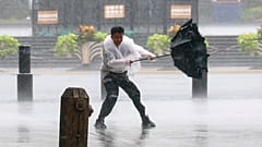Homem tenta segurar o guarda-chuva sob vento forte e chuva antes do tufão Dolphin, no distrito de Huangpu, Xangai, China, domingo, 9 de agosto de 2026