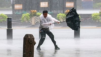 Shanghai: un homme lutte pour garder son parapluie sous le vent et la pluie avant le typhon Dolphin