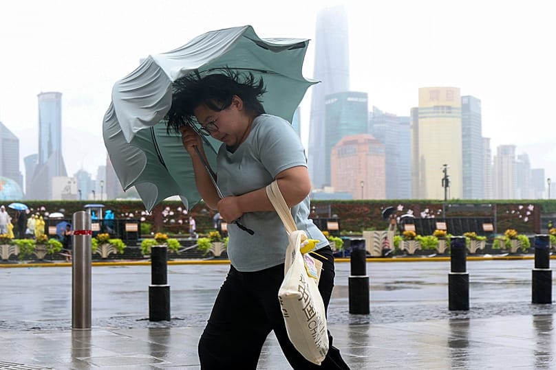 A woman struggles with her umbrella in strong wind and rain ahead of Typhoon Dolphin at Huangpu District of Shanghai on Sunday, 9 August 2026.