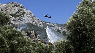 A firefighting helicopter drops water after a wildfire in Kruja, north of Tirana, Albania, Sunday, Aug. 9, 2026. (AP Photo/Hameraldi Agolli)