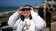Une femme portant des lunettes spéciales regarde l'éclipse solaire depuis la plage d'Ericeira, près de Lisbonne, le samedi 29 mars 2025.