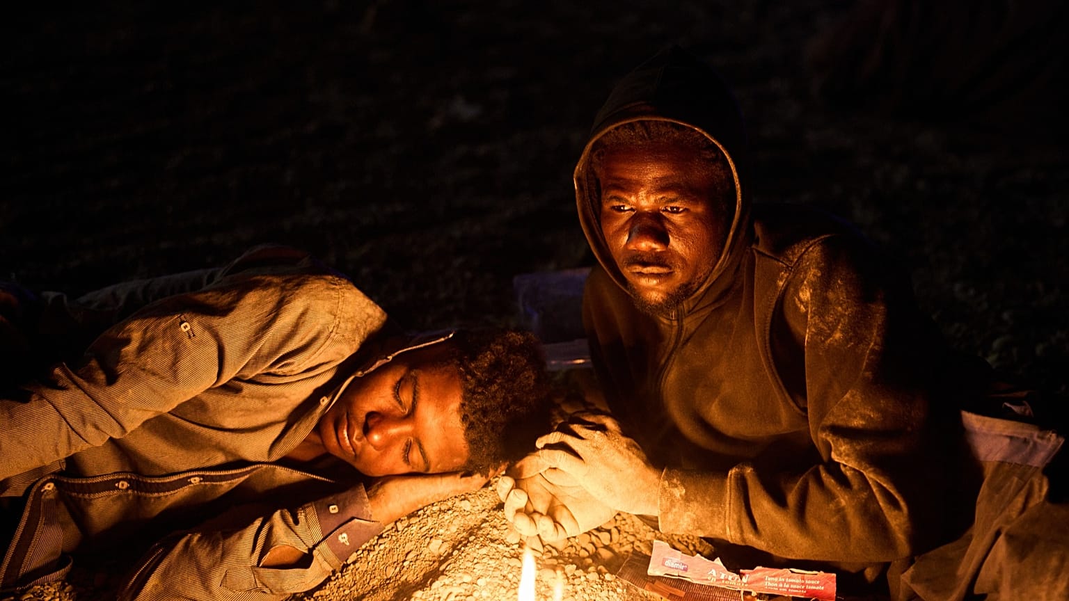Migrantes que cruzaron a España desde Marruecos se reúnen alrededor de una hoguera en una playa del enclave español de Ceuta, el lunes 3 de agosto de 2026.