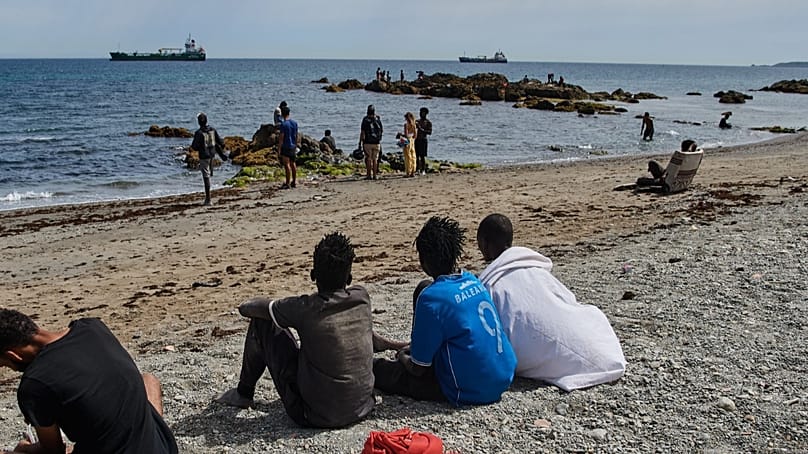 Migrantes que cruzaron a España desde Marruecos se congregan en una playa del enclave español de Ceuta, el lunes 3 de agosto de 2026. (Foto AP/Antonio Sempere)
