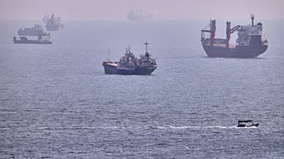 АРХИВ: Небольшая лодка проходит мимо грузовых и других коммерческих судов, стоящих на якоре в Ормузском проливе у Бендер-Аббаса, 5 августа 2026 года
