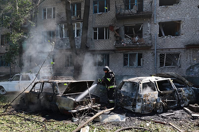 Rescue workers try to put out a fire of a residential building and cars burning after a Russian air guided bomb strike in Zaporizhzhia, 10 August, 2026