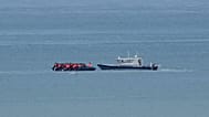 A boat thought to carry migrants is escorted by a vessel from the French Gendarmerie Nationale in the English Channel off Wimereux beach, 4 September, 2024