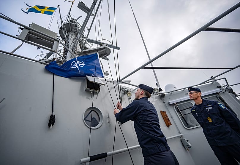 Bandeira da NATO içada no navio de patrulha HMS Carlskrona (P04), que parte do porto naval de Karlskrona, 4 de fevereiro de 2025
