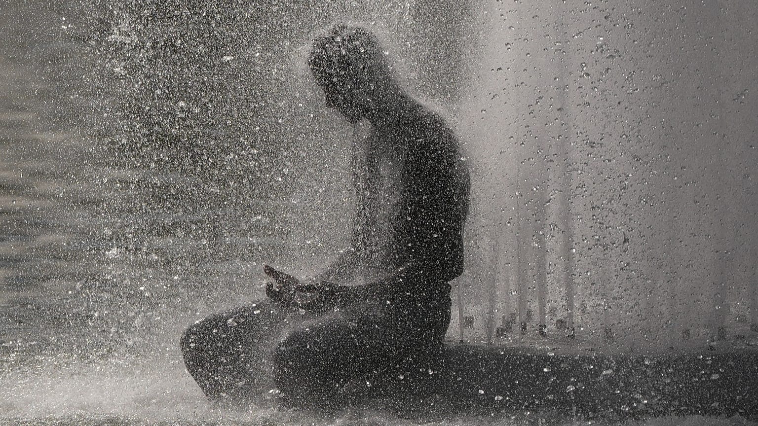 A person cools off at Trocadero fountain near the Eiffel Tower during a heat wave in Paris, 24 June, 2026