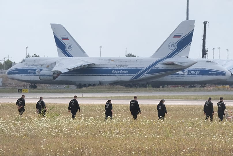 Police officers walking across a field on the grounds of Leipzig Airport, 7 August, 2026