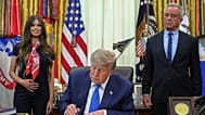 President Donald Trump signs an executive order about vaccines as Jayme Franklin, left, and Health and Human Services Secretary Robert F. Kennedy Jr. watch Monday, Aug. 10, 20