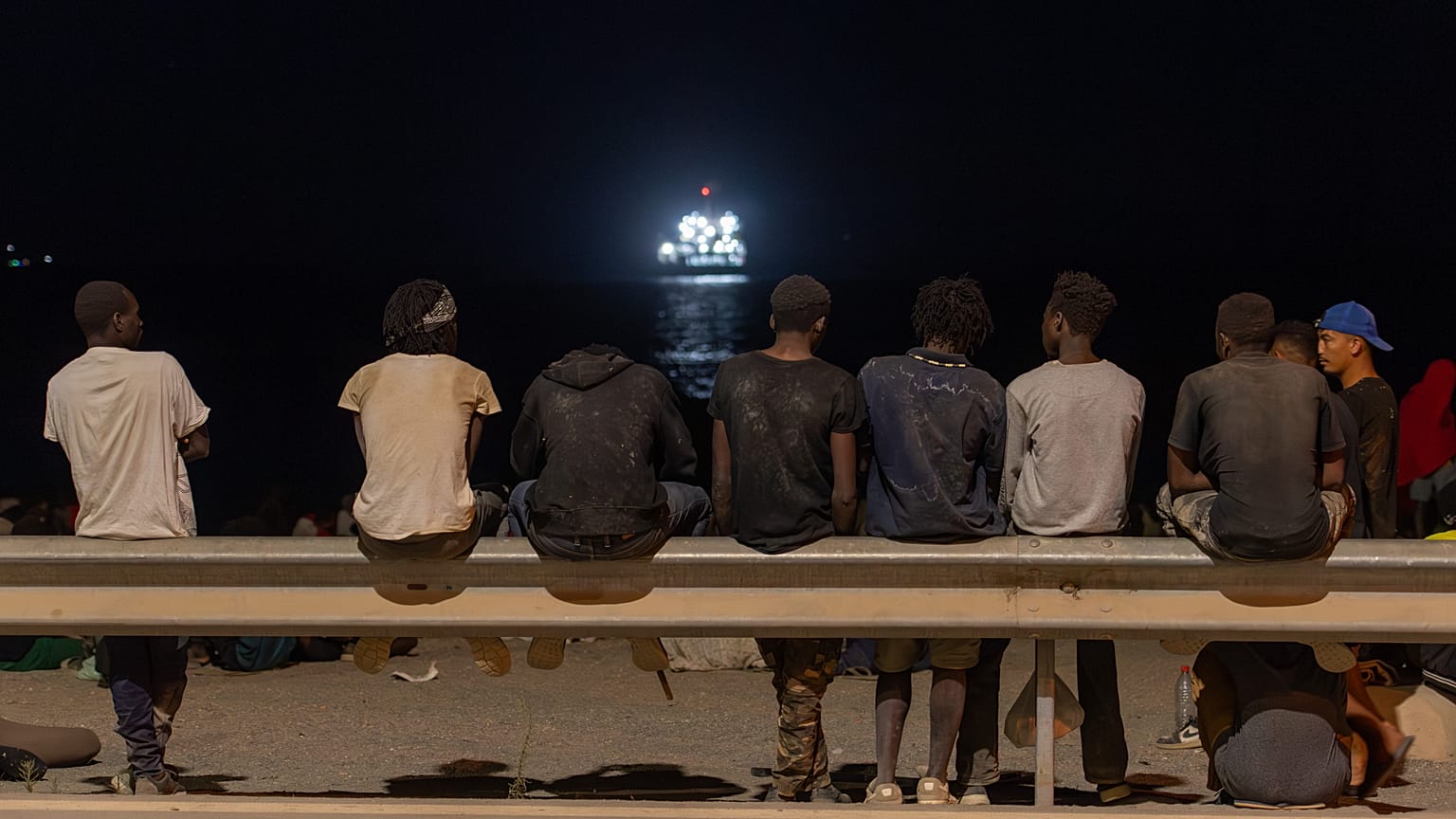 Migrants who crossed into Spain from Morocco gather on a beach in the Spanish enclave of Ceuta, Sunday, Aug. 2, 2026. (AP Photo/Antonio Sempere)