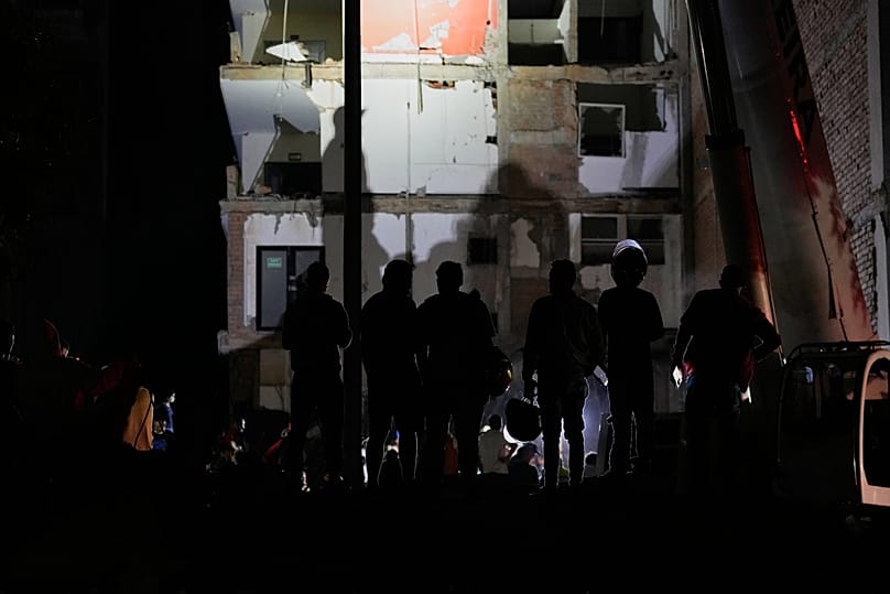 Varios trabajadores observan los desperfectos de un edificio mientras cae la noche en Pereira, Colombia, el lunes 10 de agosto de 2026