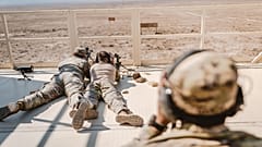 Soldados com uniforme de camuflagem treinam técnicas de franco-atirador num cenário desértico
