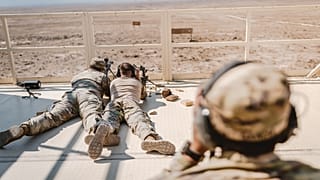 Soldados con uniformes de camuflaje practicando habilidades de francotirador en un entorno desértico.