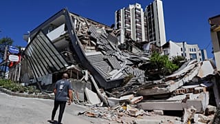 A man looks at a collapsed building after an earthquake struck Manizales
