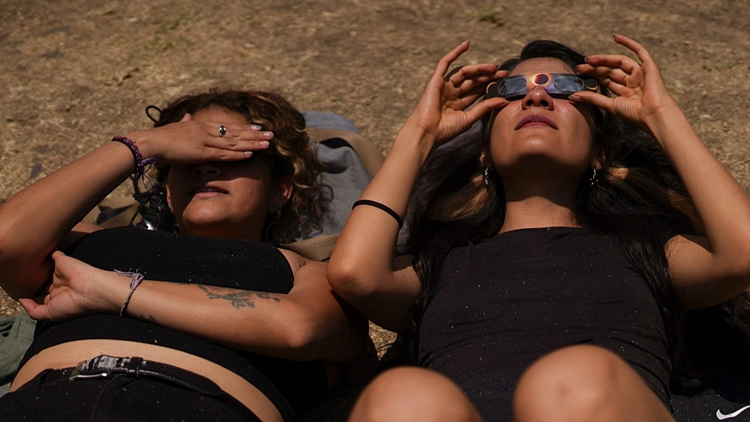 Several people lie on the ground to watch the total solar eclipse at UNAM University in Mexico City, Monday 8 April 2024. (AP Photo/Marco Ugarte)