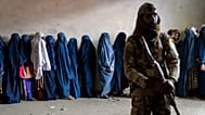 FILE - A Taliban fighter stands guard as women wait to receive food rations distributed by a humanitarian aid group, in Kabul, Afghanistan, on 23 May, 2023.