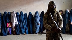 ARŞİV - 23 Mayıs 2023'te Afganistan'ın Kabil kentinde bir Taliban savaşçısı, yardım kuruluşundan gıda yardımı bekleyen kadınlara nöbet tutuyor.