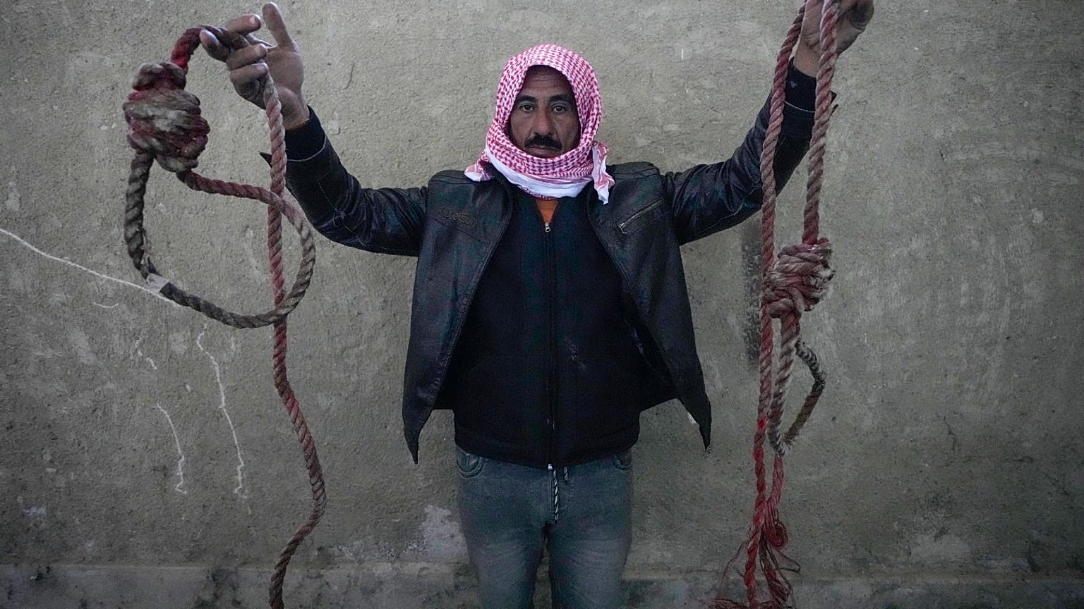 رجل يحمل حبلين مربوطين على شكل حبال مشنقة، تم العثور عليهما في سجن صيدنايا العسكري سيئ السمعة، شمال دمشق، سوريا، الاثنين 9 ديسمبر 2024.