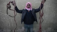رجل يحمل حبلين مربوطين على شكل حبال مشنقة، تم العثور عليهما في سجن صيدنايا العسكري سيئ السمعة، شمال دمشق، سوريا، الاثنين 9 ديسمبر 2024.
