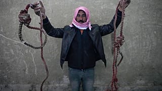 رجل يحمل حبلين مربوطين على شكل حبال مشنقة، تم العثور عليهما في سجن صيدنايا العسكري سيئ السمعة، شمال دمشق، سوريا، الاثنين 9 ديسمبر 2024.