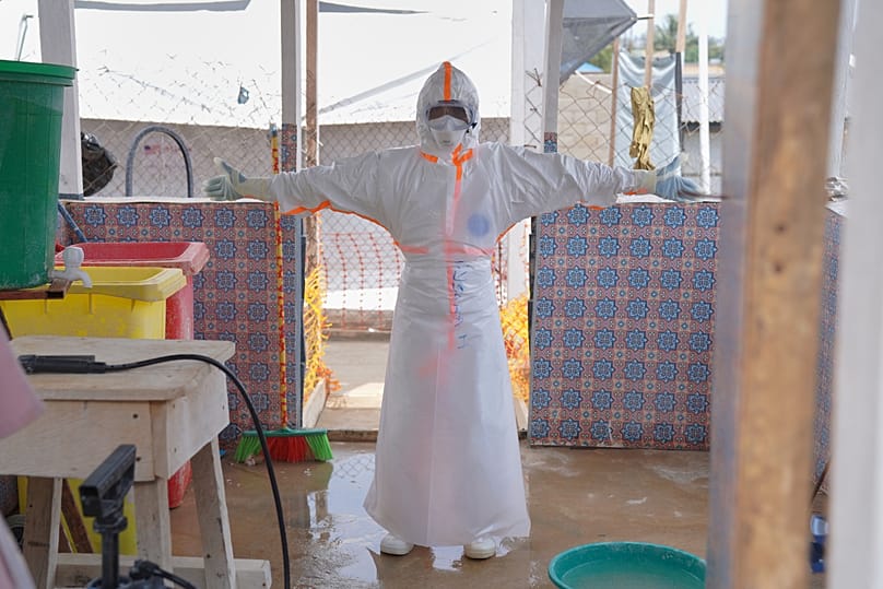 A health worker waits to be sprayed with disinfectant at the treatment centre in Bunia General Hospital in Ituri, 11 August, 2026
