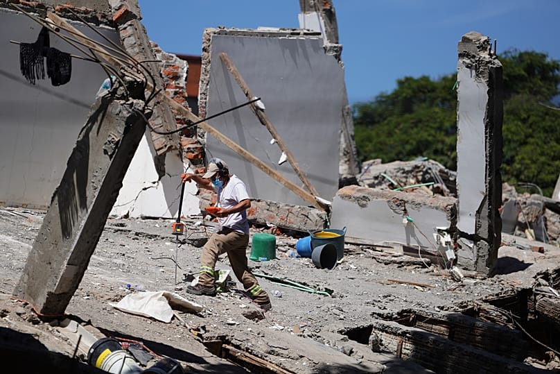 A rescue worker uses a scanner to search for signs of survivors in the debris the day after an earthquake struck Cali, Colombia, Tuesday, 11 August 2026.