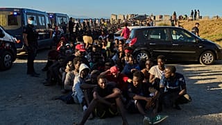 Migrants who crossed from Morocco into Spain line up for food distribution on a beach in the Spanish enclave of Ceuta, Monday, Aug. 3, 2026. 