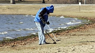 Ein Mensch sucht mit einem Metal-Detektor im Sand. (Symbolbild)
